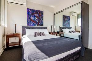 a bedroom with a large bed and a painting on the wall at Ridge Apartment Hotel in Brisbane