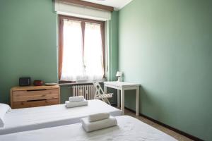 sypialnia z 2 łóżkami, oknem i biurkiem w obiekcie YouHosty - Suzzani 269 w Mediolanie