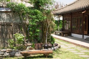 a garden with pots and a bench next to a building at Ginkgo Tree Guesthouse in Jeonju