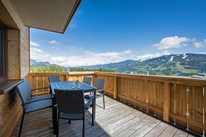 eine Terrasse mit einem Tisch, Stühlen und Bergen in der Unterkunft Chalet Kulmberg in Ramsau am Dachstein