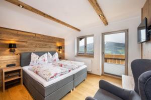 Schlafzimmer mit einem Bett, einem TV und Fenstern in der Unterkunft Chalet Kulmberg in Ramsau am Dachstein