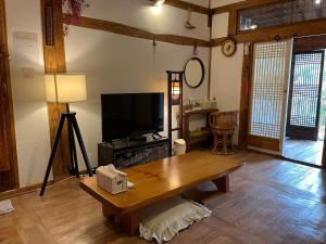 a living room with a television and a wooden table at Ginkgo Tree Guesthouse in Jeonju
