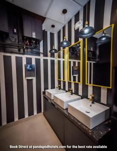 a bathroom with three sinks and two mirrors at Panda Pod Hotel in Richmond