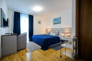 a hotel room with a blue bed and a chair at Hotel Belvedere in Sukošan