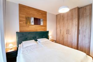 a bedroom with a large white bed with wooden cabinets at LAGUNA Apartament Polanica Residence 43 in Polanica-Zdrój