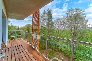 een balkon met een bank en uitzicht op de bossen bij LAGUNA Apartament Polanica Residence 43 in Polanica-Zdrój