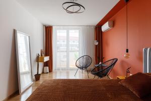 sypialnia z 2 krzesłami i pomarańczową ścianą w obiekcie Roof Rooms w Iwano-Frankiwsku