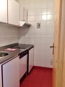 eine Küche mit weißen Schränken und einem roten Boden in der Unterkunft Appartamenti Coin Au Paradis in Breuil-Cervinia