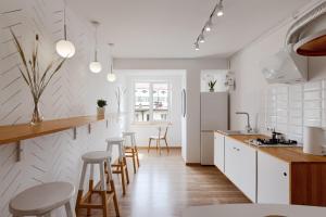 a kitchen with white cabinets and bar stools at Roof Rooms in Ivano-Frankivsʼk
