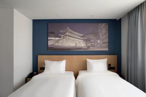 2 camas en una habitación con una foto en la pared en Travelodge Myeongdong City Hall, en Seúl