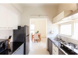 a kitchen with a black refrigerator and a table at BluO 1BR Hitech City - Balcony, Gym, Terrace Garden in Hyderabad