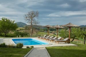 a swimming pool with lounge chairs and umbrellas at Puhek breg in Krapina