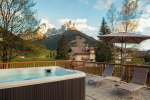 a hot tub with chairs and an umbrella on a deck at X Alp Hotel in Pozza di Fassa