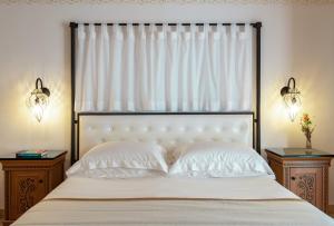 a bedroom with a white bed with two night stands at Mitsis Selection Blue Domes in Kardamaina
