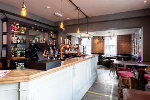 a bar in a restaurant with a counter and tables at The Lazy Pug in Shipston on Stour