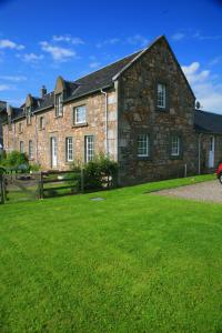 una gran casa de piedra con un patio verde en Arndean Cottages en Dollar