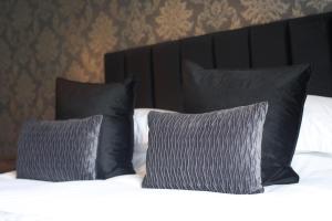 a bed with black pillows and white sheets at Glyn Valley Hotel in Llansantffraid Glyn Ceiriog