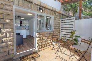 een terras met een tafel en stoelen tegen een bakstenen muur bij NoMADS in Hvar