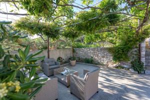 een patio met rieten meubels en een stenen muur bij NoMADS in Hvar