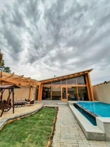 a house with a swimming pool and a patio at شاليهات توت الريفية بالطائف in Al Muraysīyah