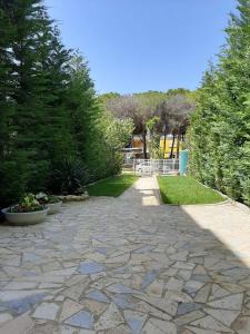 kamienny chodnik w ogrodzie z krzakami i drzewami w obiekcie Villa Leyland w mieście Golem
