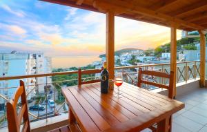 una mesa de madera con una copa de vino en el balcón en LIDO APARTMENTS, en Himare