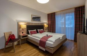 a bedroom with a bed, chair, and nightstand at Pradas Resort Brigels in Breil/Brigels