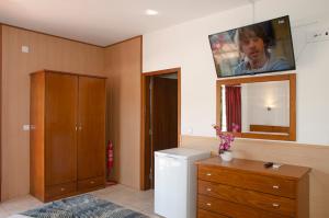 a bathroom with a tv on the wall above a refrigerator at Praia das Rocas Bungalows in Castanheira de Pêra