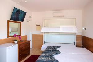 ein Schlafzimmer mit einem weißen Bett und einer Kommode mit einer Mikrowelle in der Unterkunft Praia das Rocas Bungalows in Castanheira de Pêra