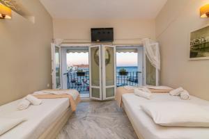 three beds in a room with a balcony at Fratelli Rooms in Tinos Town