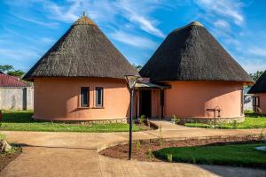 two huts with thatched roofs in a park at Hunters Paradise Cottages in Bungoma