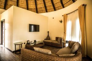 a living room with wicker furniture and a tv at Hunters Paradise Cottages in Bungoma