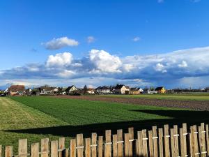 uma cerca em frente a um campo com casas em Maison de Rêve en Alsace - Chez Maïdala 3 étoiles em Houssen