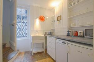 uma cozinha com armários brancos, um lavatório e uma janela em 34 Notre Dame - PRETTY TRIPLEX HOUSE IN HONFLEUR-NEAR THE OLD PORT em Honfleur