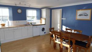 a kitchen with a table and a blue wall at Arndean Cottages in Dollar