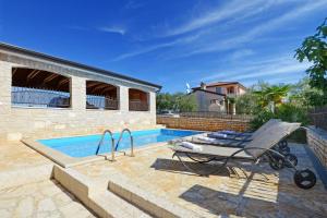 a swimming pool with a lounge chair next to a house at Villa Bianca in Tar