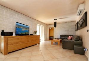 a living room with a flat screen tv on a wooden cabinet at Villa Bianca in Tar