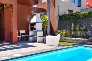 a backyard with a swimming pool and a grill next to a house at Sol 21 by VillaGranCanaria in Arguineguín