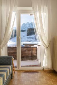 a room with a sliding glass door with a view of a snowy mountain at Pension Haunold in San Candido