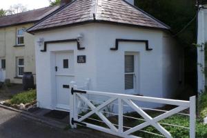 a small white building with a gate and a fence at The Welsh Toll House in Carmarthen