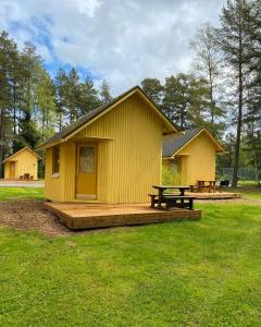 mały żółty budynek ze stołem piknikowym i ławką w obiekcie Yyteri Camping Cottages w mieście Yyteri