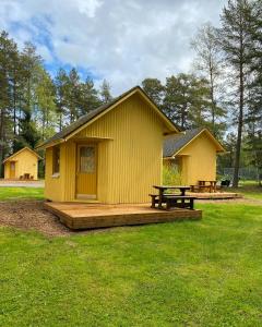 un pequeño edificio amarillo con una mesa de picnic y un banco en Yyteri Camping Cottages, en Yyteri