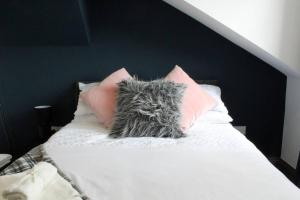a white bed with pink and grey pillows on it at StayWell Apt By Horizon Stays in Middlesbrough