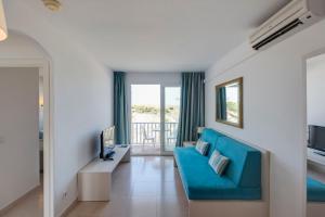 a living room with a blue couch and a television at Seth Isla Paraiso in Arenal d'en Castell