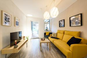 a living room with a yellow couch and a tv at Ackerbürgerhof Ballstraße 18 in Quedlinburg