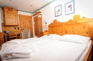 een slaapkamer met een groot wit bed met een houten hoofdeinde bij Berghotel Arthurhaus in Mühlbach am Hochkönig