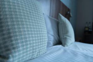 um close-up de uma cama com lençóis brancos e almofadas em The Buxted Inn em Buxted