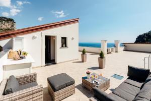 a patio with furniture and the ocean in the background at Charming House in Amalfi