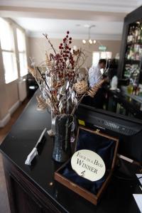 The Buxted Inn في Buxted: طاولة سوداء مع مزهرية مع الزهور وإشارة