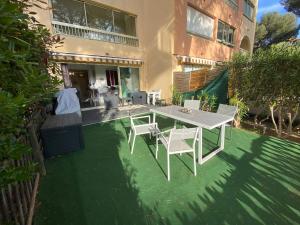 een patio met een witte tafel en stoelen voor een gebouw bij Boost Your Immo Six Fours Les Plages Pinèdes Aryana 477 in Six-Fours-les-Plages